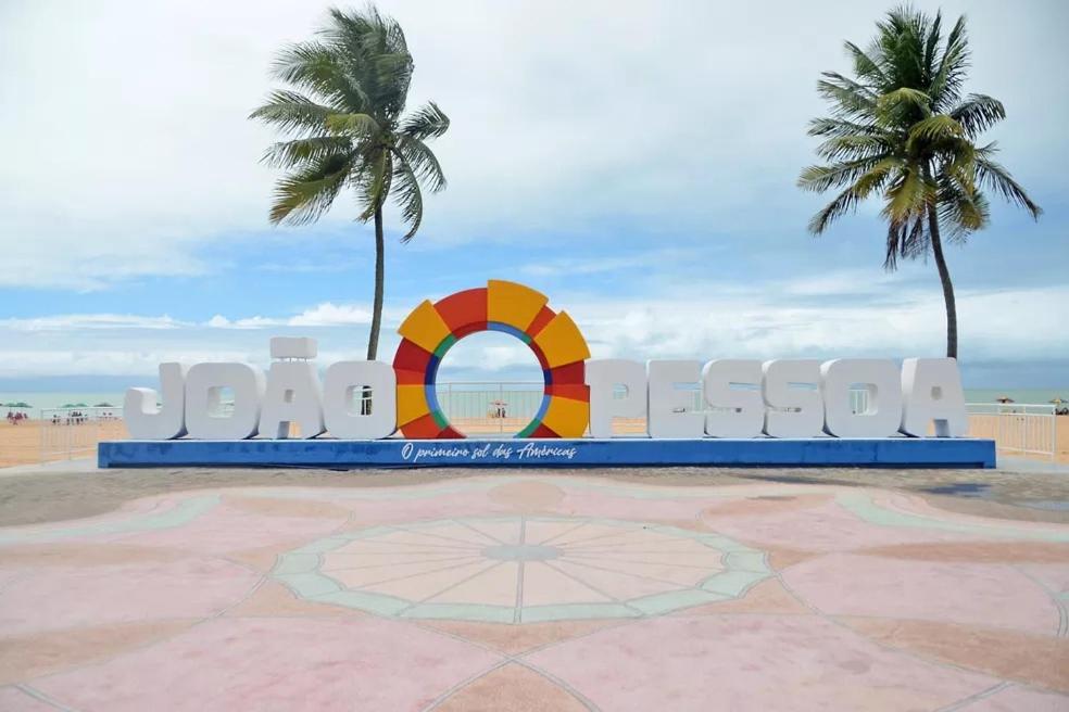 uma placa na praia com duas palmeiras em Cabo Branco Dream em João Pessoa