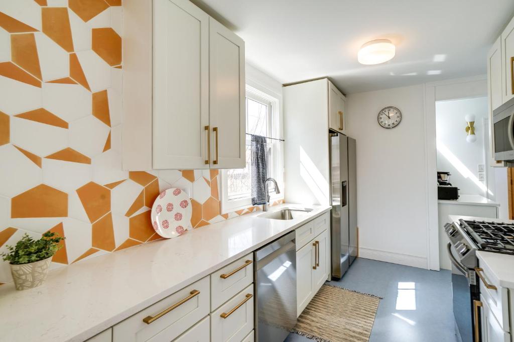 a kitchen with white cabinets and a geometric wall at Charming and Updated Home in Howe Neighborhood! in Minneapolis