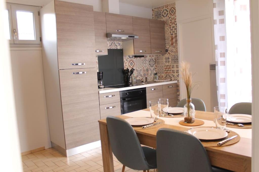 una cucina con tavolo in legno con sedie e una sala da pranzo di Le Saint-Amour appartement classé 2 étoiles a Saint-Amour