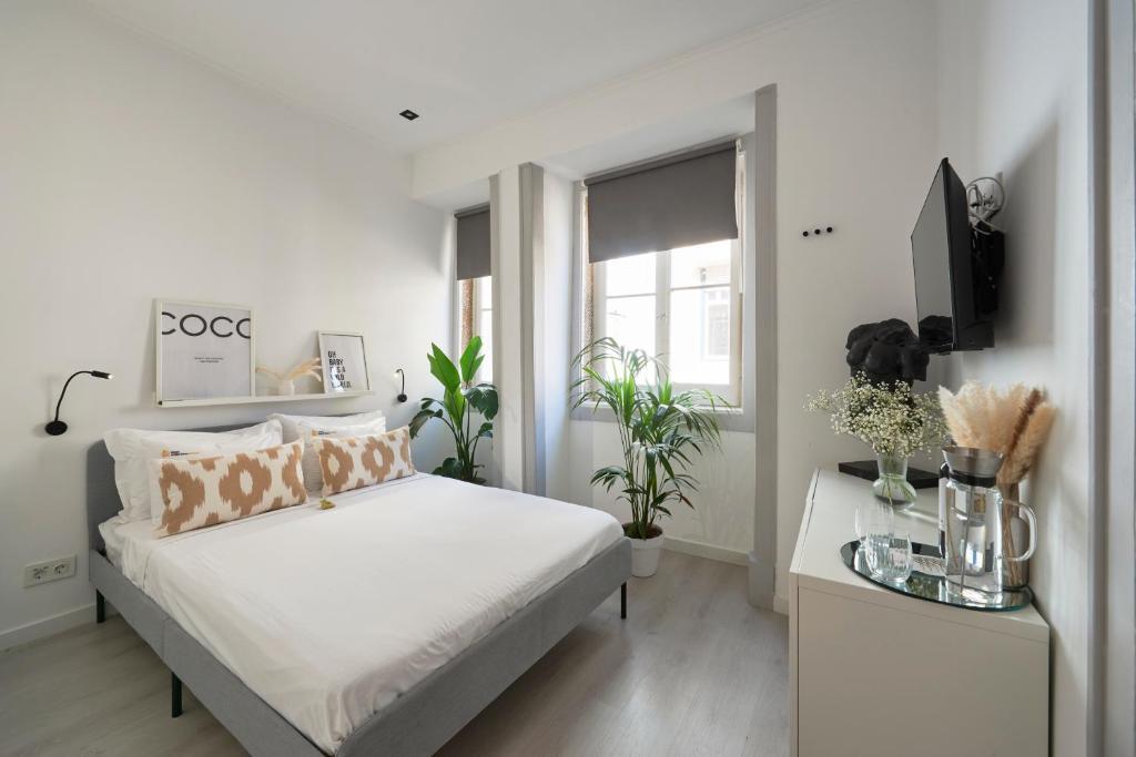 - une chambre blanche avec un lit et une télévision dans l'établissement Lisboa nova Central - bica 2E, à Lisbonne