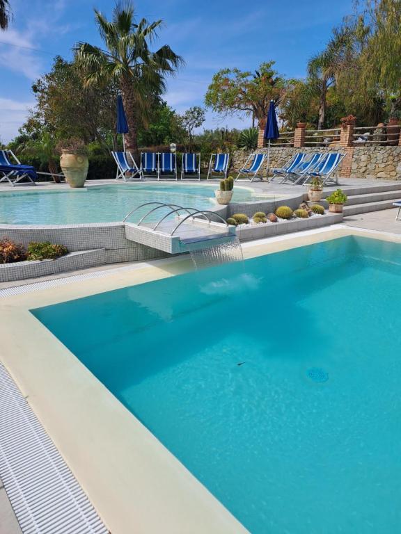 a swimming pool with blue water and lounge chairs at agriturismo heaven in Capo Vaticano