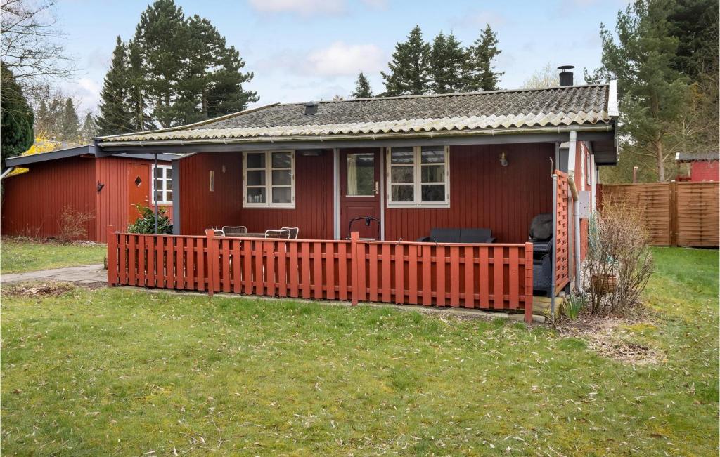 una casa roja con una valla de madera en el patio en Stunning Home In Prst With Kitchen, en Præstø