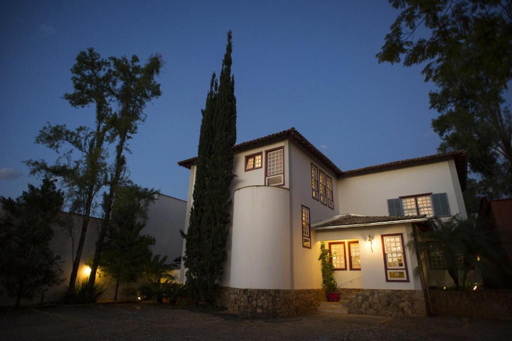 Una casa blanca con un árbol delante. en Pousada Bárbara Bela en Tiradentes