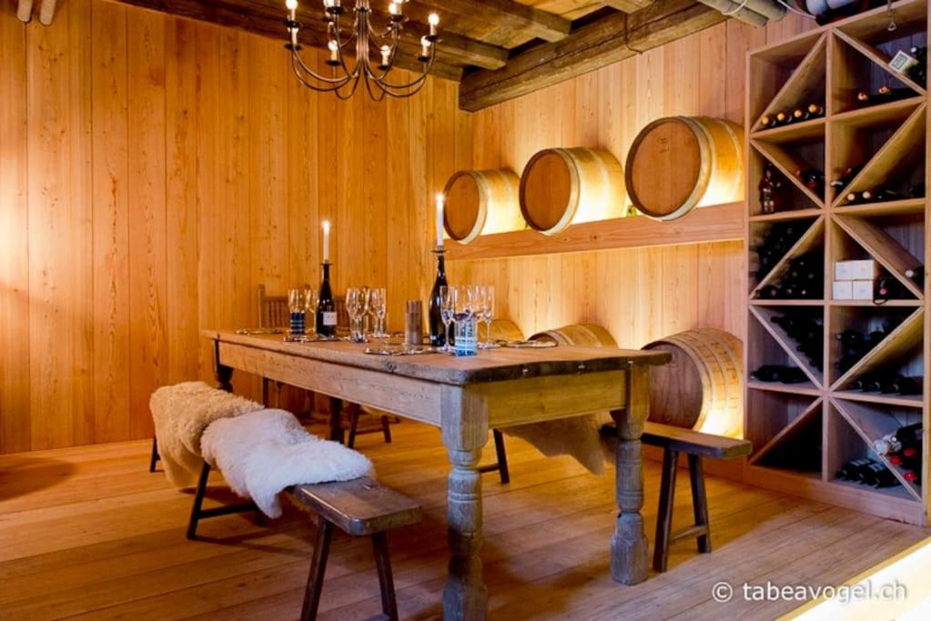 uma sala de jantar com mesa e barris de vinho em Luxury stay in 250 year old wine farm house and gardens em Rüschlikon