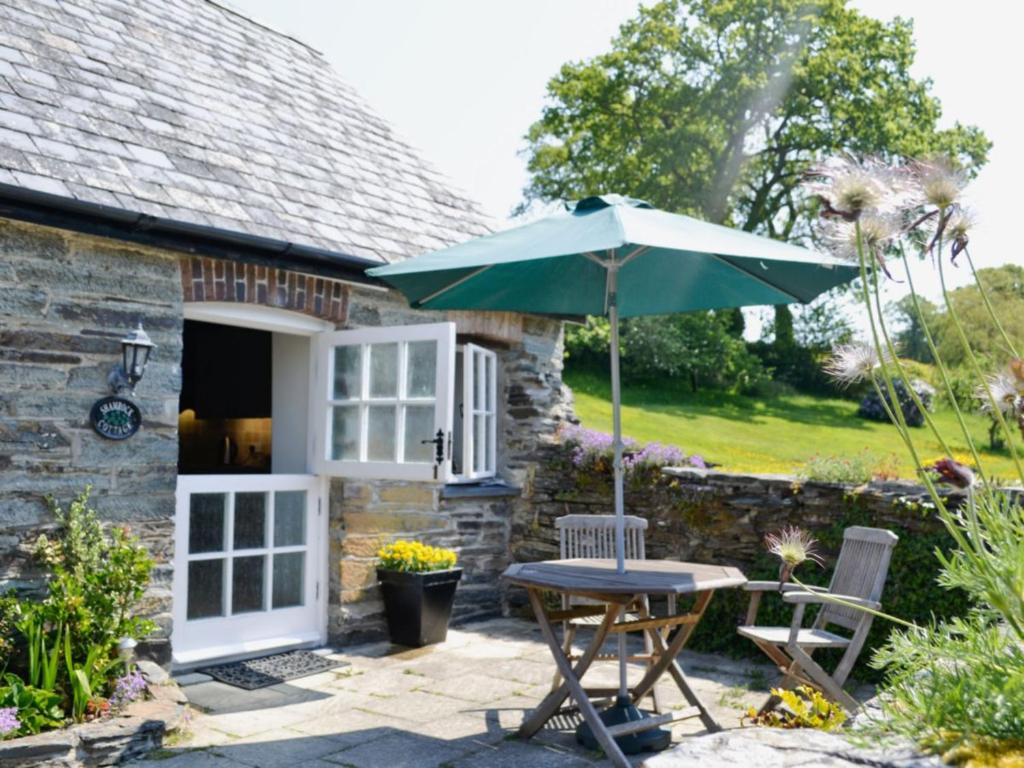 un patio con sombrilla, mesa y sillas en Shamrock Cottage en Cenarth