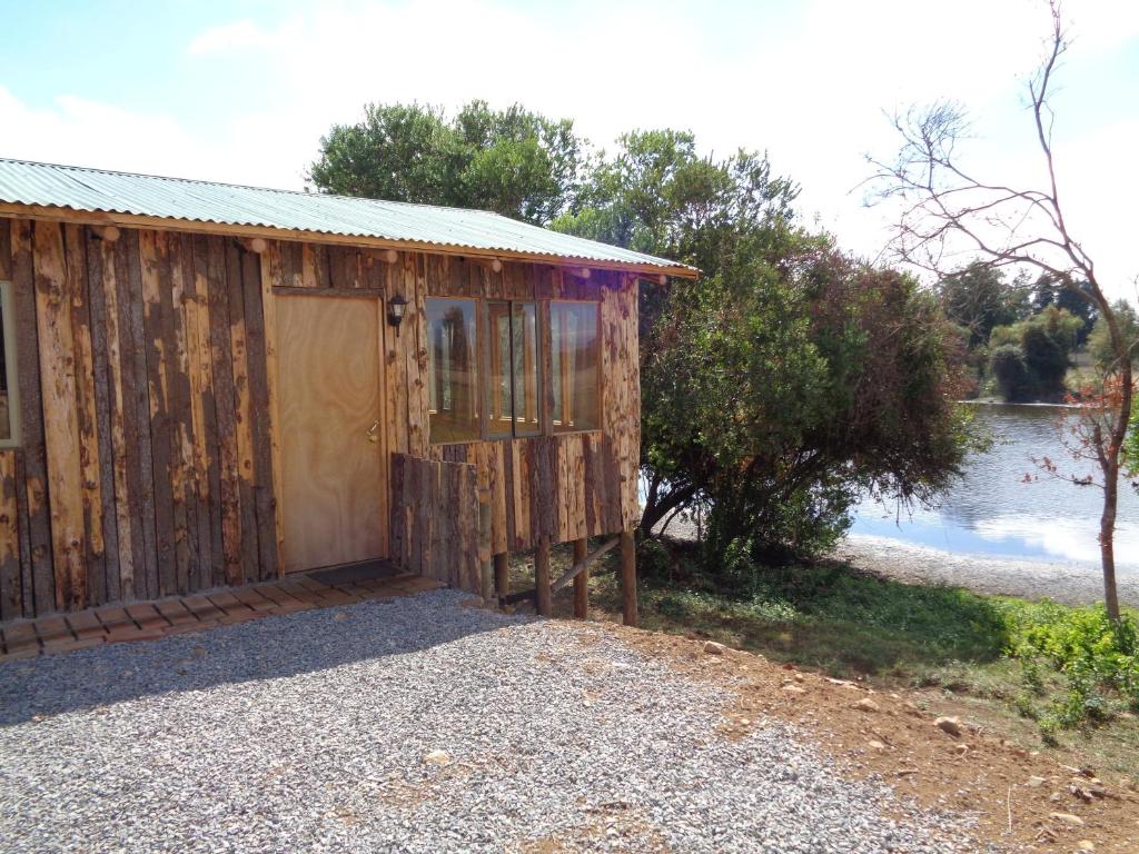 un cobertizo de madera con una puerta frente a un lago en Cabañas de la Laguna, en Parral