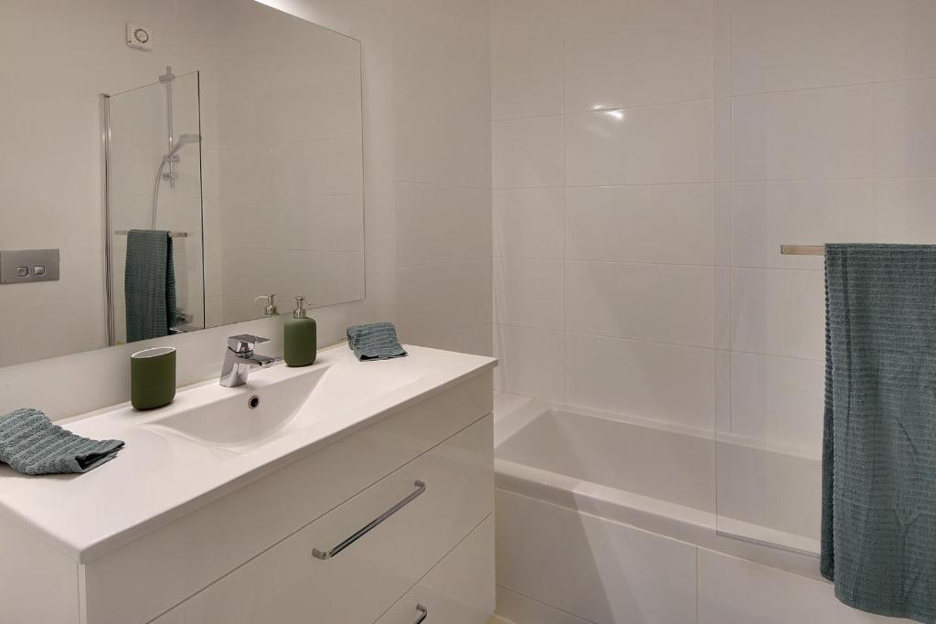 a white bathroom with a sink and a shower at Casinha do Sol in Almancil