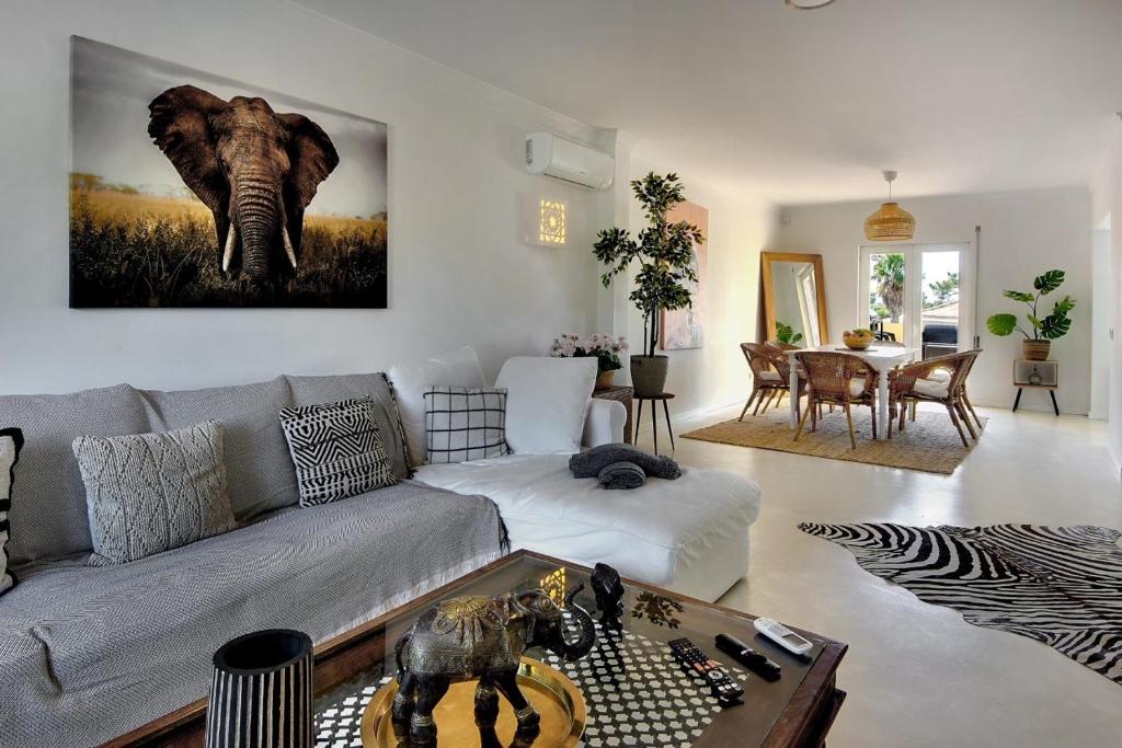 a living room with an elephant painting on the wall at Casinha do Sol in Almancil