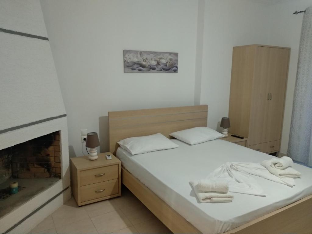 - une chambre avec un lit doté de draps blancs et une cheminée dans l'établissement Alex apartment, à Saranda