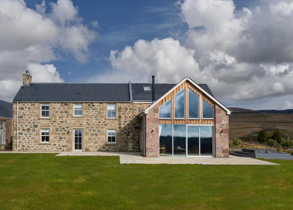 a large stone house with large windows at Kipney Farmhouse - luxury hunting lodge in Perth