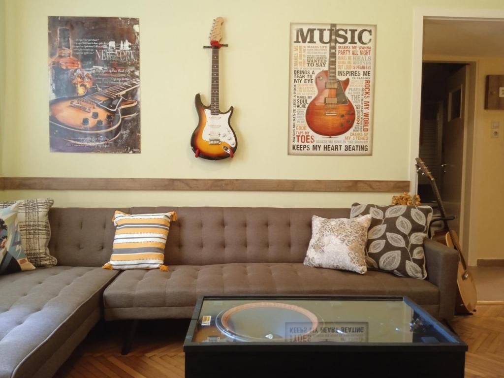 sala de estar con sofá y 2 guitarras en la pared en Still got the blues, en Atenas