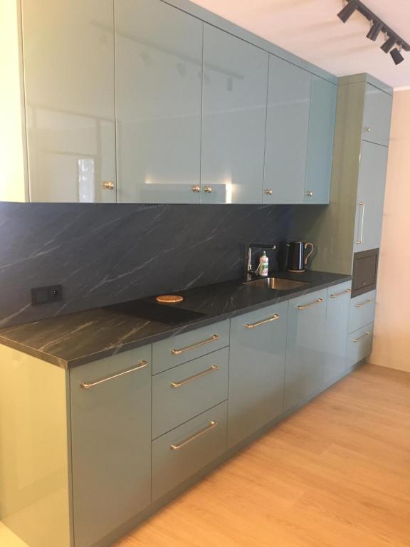 eine Küche mit grauen Schränken und einer schwarzen Arbeitsplatte in der Unterkunft Lazurowy Apartament in Łeba