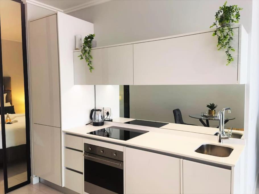 a kitchen with white cabinets and a sink at Executive Suite at Ellipse in Waterfall Midrand in Midrand