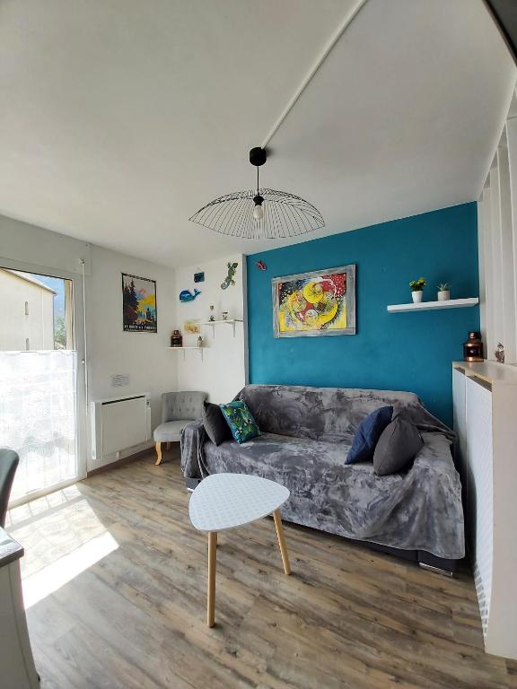 a living room with a couch and a blue wall at Luz St Sauveur, Appartement 3 personnes, vue montagne, exposé sud, Résidence très calme in Luz-Saint-Sauveur