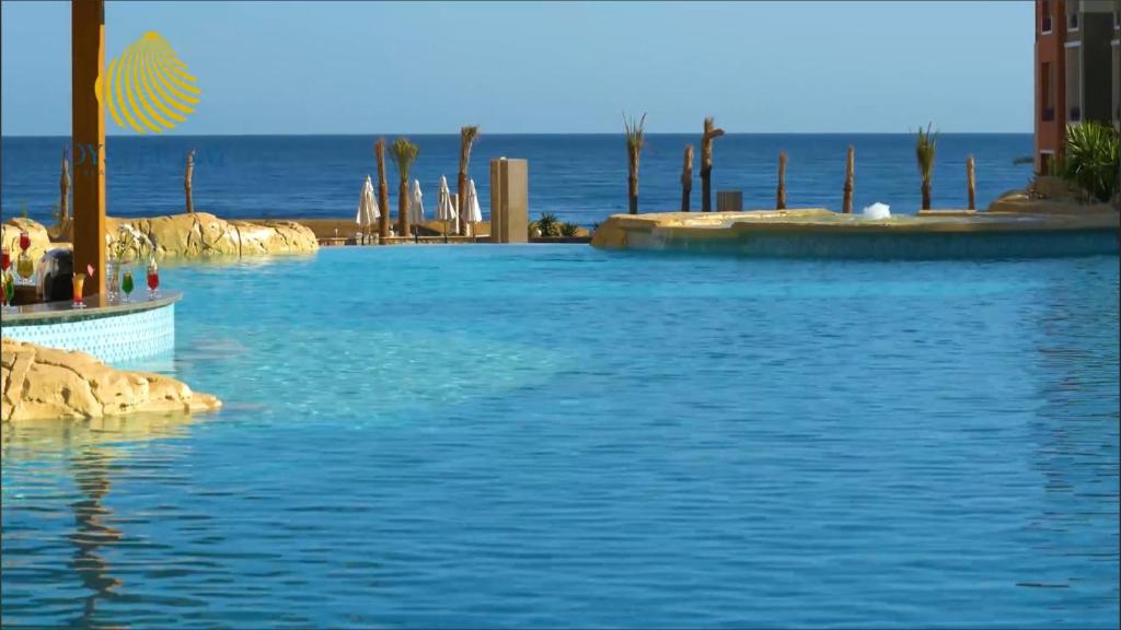 una piscina con el océano en el fondo en Oyster Bay Resort, One Bedroom Beach Front Apartment, Marsa Alam, en Abu Dabab