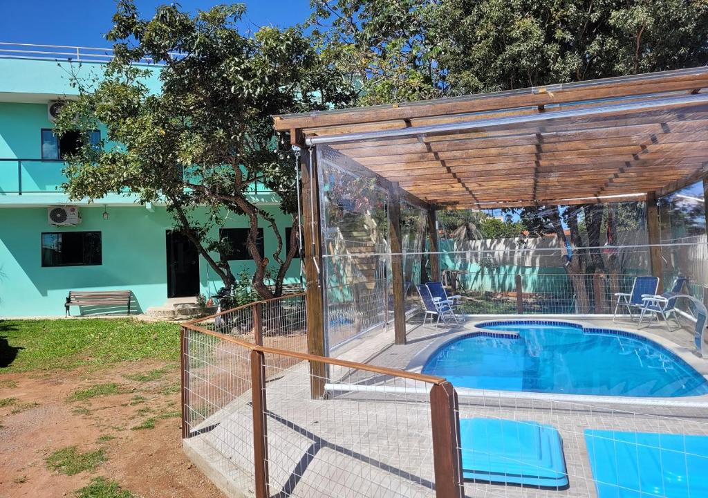 a pool with a wooden pergola next to a house at Kit Dona Branca in Alto Paraíso de Goiás