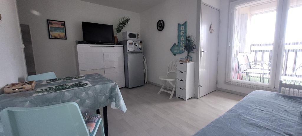 a room with a table and a kitchen with a refrigerator at Palm Appart in Biscarrosse-Plage