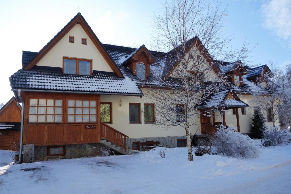 une grande maison avec de la neige au sol dans l'établissement Privát Kováč, à Vysoké Tatry