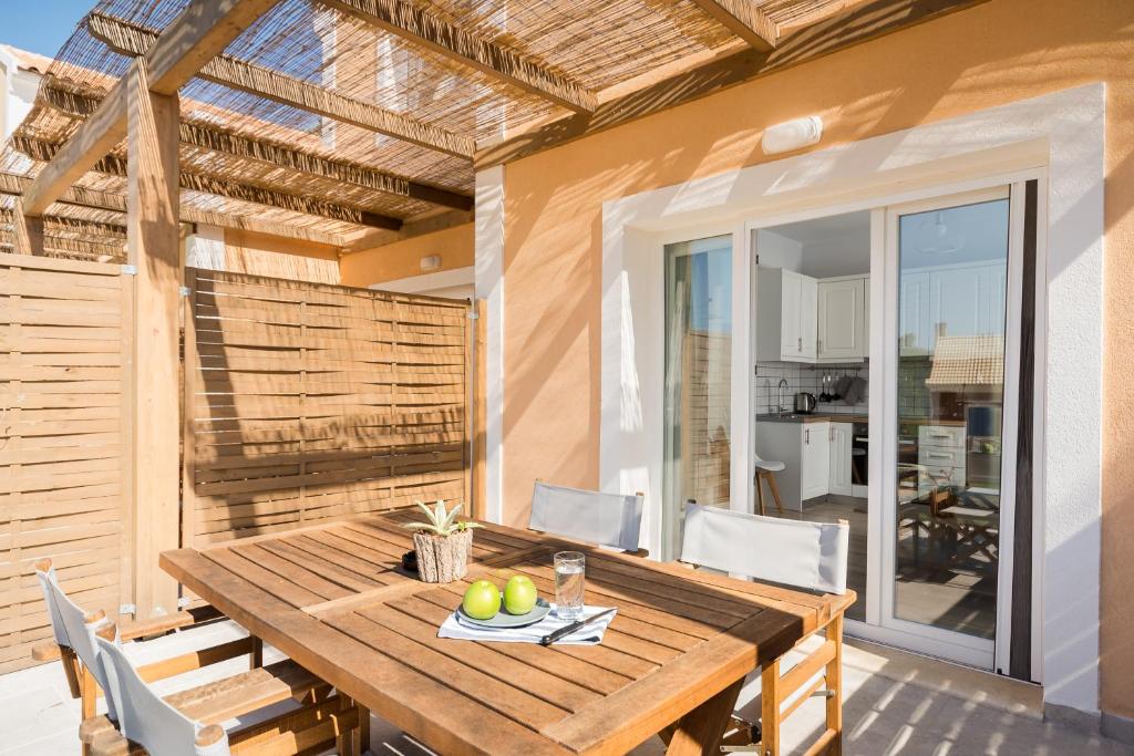 a wooden table and chairs on a patio at Reiki Apartments in Ereikoússa