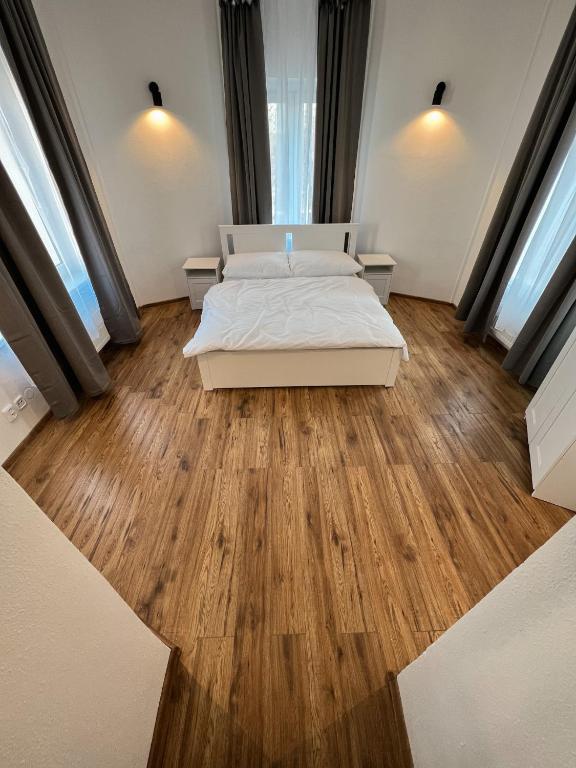 a bedroom with a bed and wooden floors and windows at Hotel & Cafe SokoLOVE in Sokolov