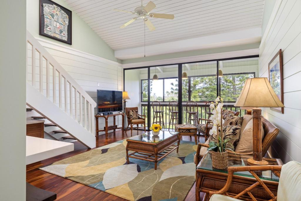 a living room with a ceiling fan and a table at Spectacular golf course front in Kahuku