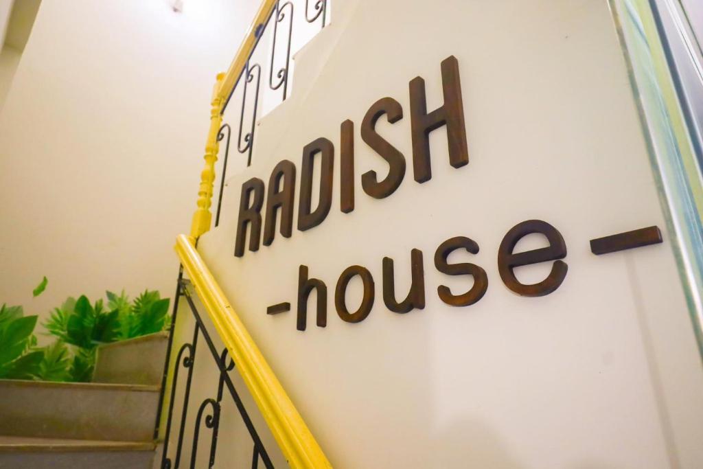 a sign for a hotel house on a wall at Radish Cathedral Homestay in Hanoi