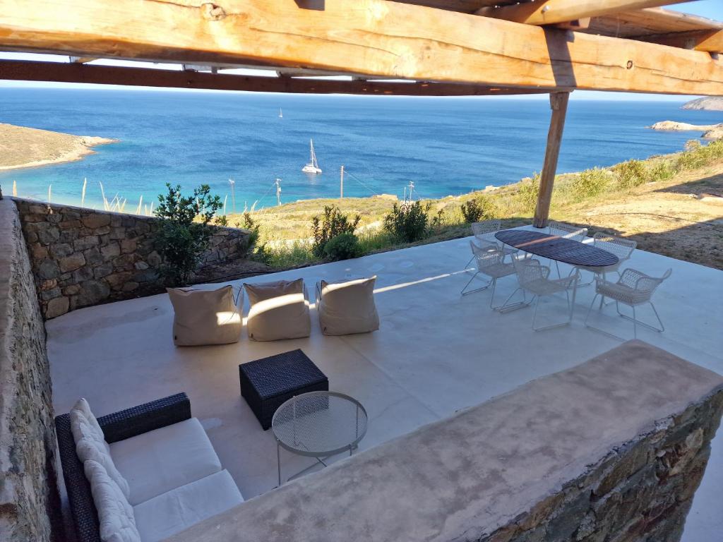 patio z krzesłami i stołami oraz widokiem na ocean w obiekcie Blue Sea Villa w mieście Serifos Chora