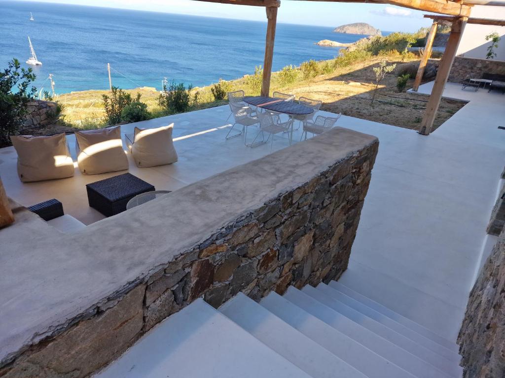 a patio with a table and chairs and the ocean at Blue Sea Villa in Serifos Chora