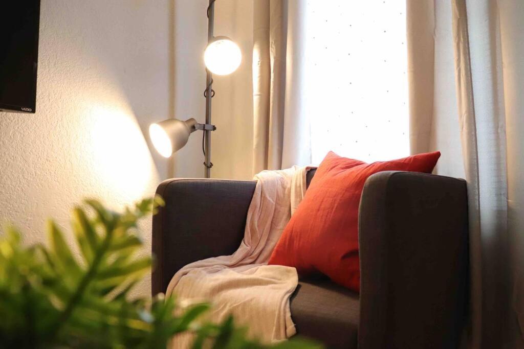 un sofá con una almohada roja junto a una ventana en Cozy 2-Bedroom Rental Unit, en Eagle Pass