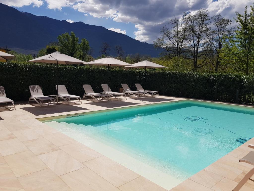 a swimming pool with lawn chairs and umbrellas at Hotel Diana in Boario Terme