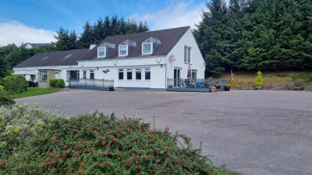 uma grande casa branca com uma grande entrada em Lochbroom Lodge em Ullapool