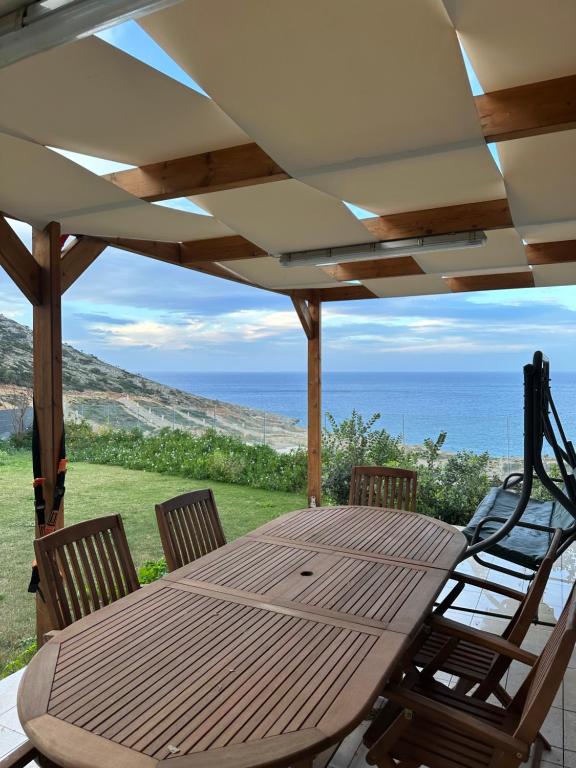 a wooden table and chairs on a patio with the ocean at Brand new studio Sea View in Agia Pelagia