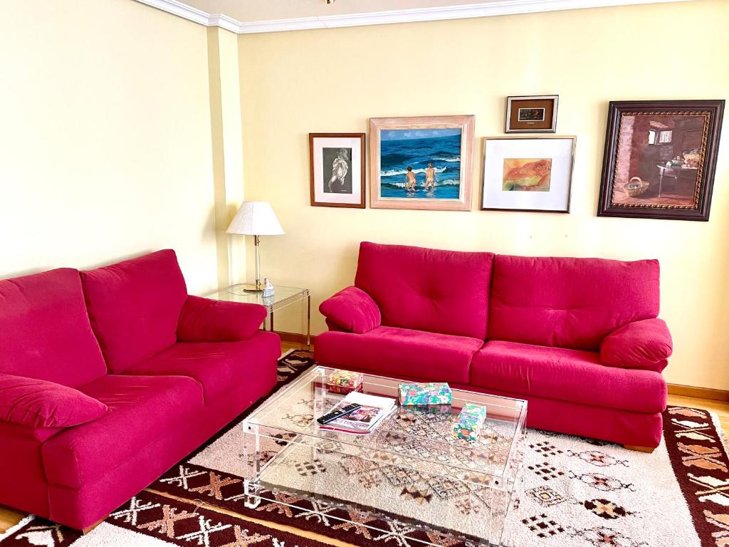 a living room with a red couch and a table at APARTAMENTO CARMEN in Gijón