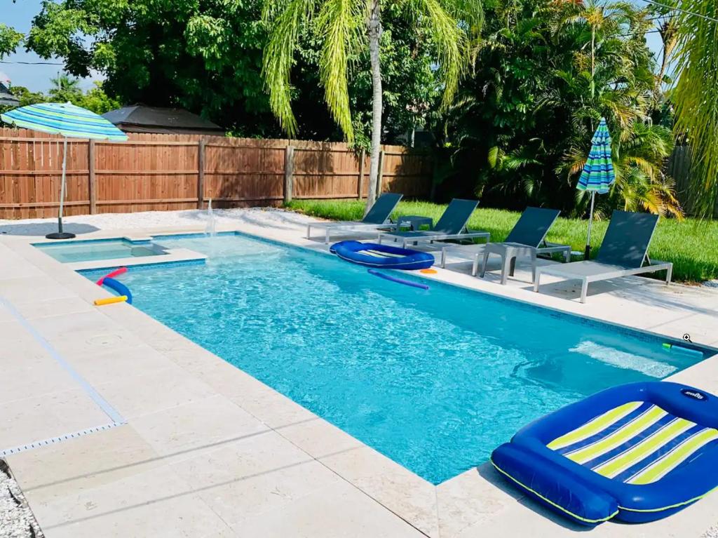 a swimming pool with lounge chairs and an umbrella at Little Beach House w/ POOL&SPA - 5 minutes to Vanderbilt Beach (Pet Friendly) in Naples
