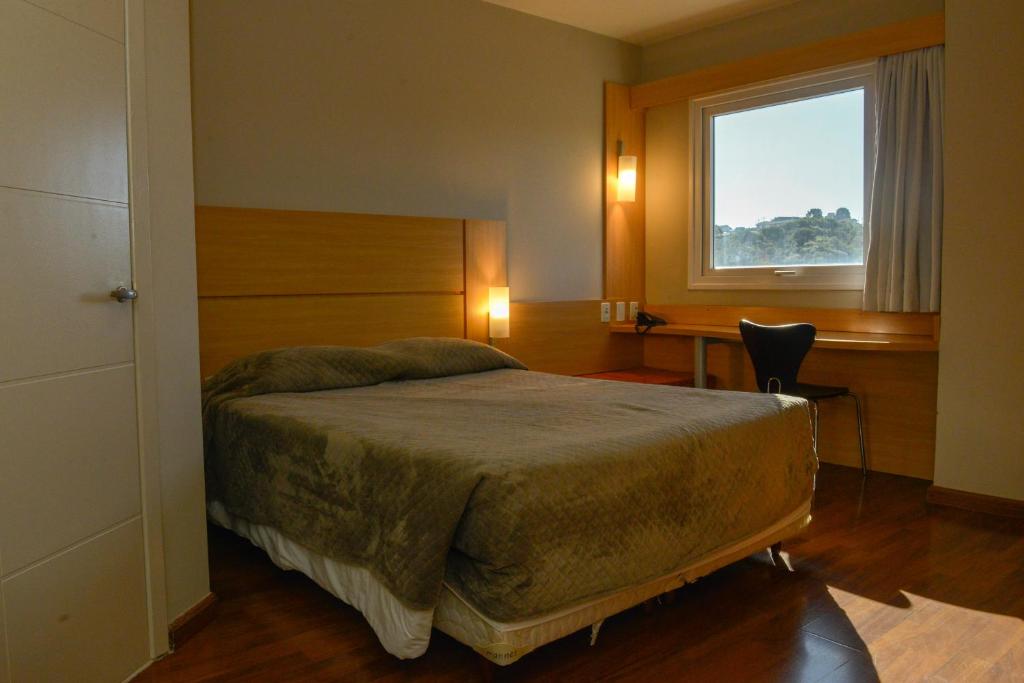 a bedroom with a bed and a window and a desk at Zago Hotel in Lages