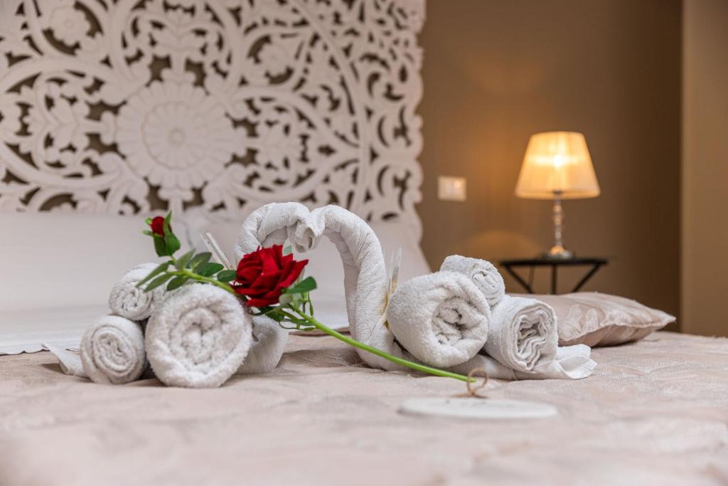 un gruppo di asciugamani su un letto con una rosa di AGORA' Castelnuovo della Daunia a Castelnuovo della Daunia