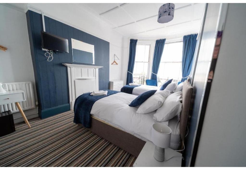 a bedroom with a large bed with blue walls at OYO Lord Kitcheners Guest House in Lowestoft