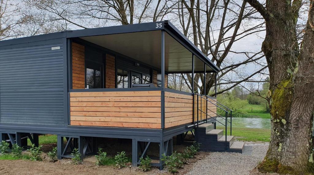 a tiny house sitting next to a tree at GM House, mobile house near Kolpa river in Metlika