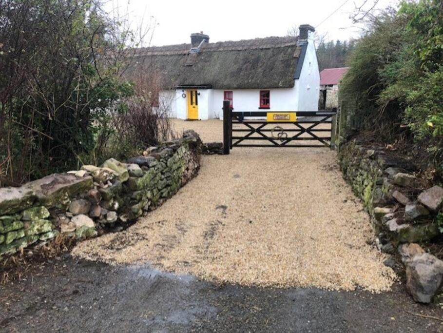 a white house with a gate and a stone wall at Sweet Meadow A delightful romantic thatched cottage by river Shannon on 4 acres is for peace party family or work from home in Rooskey