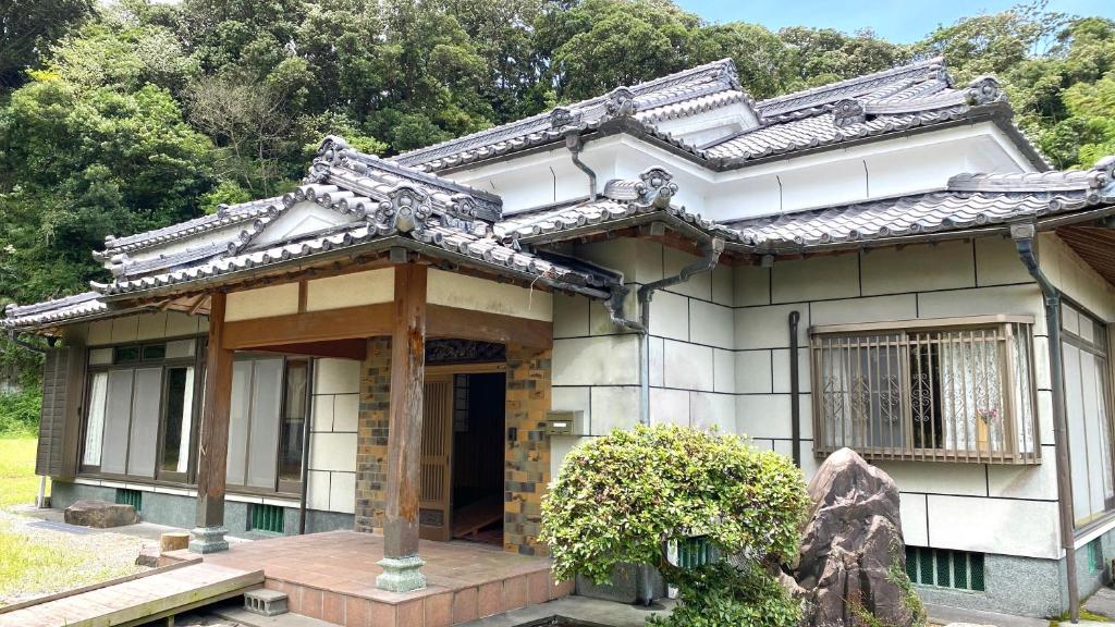 a japanese house with a roof on a garden at 旅する人生ハウス鹿屋 in Kanoya