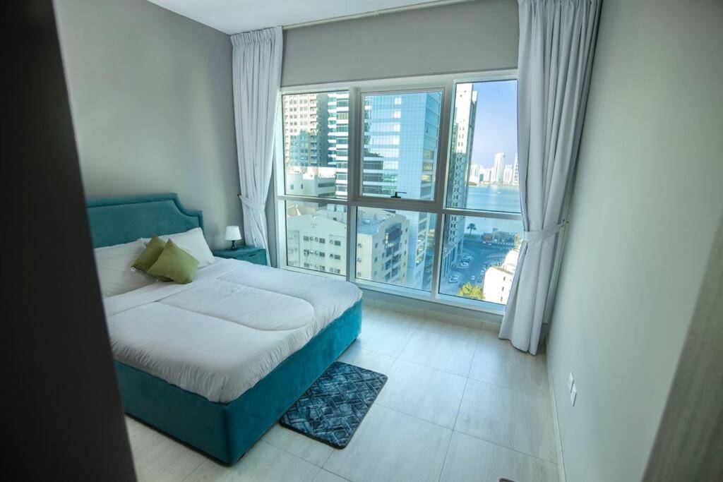 a bedroom with a bed and a large window at New Sunny spacious 2BR beach viewApt in Sharjah