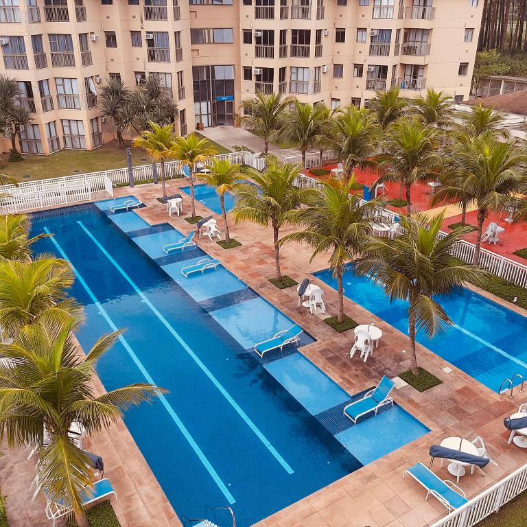 an aerial view of a resort pool with palm trees at Apartamento Reserva do Sahy - Condomínio Aldeia dos Reis in Mangaratiba