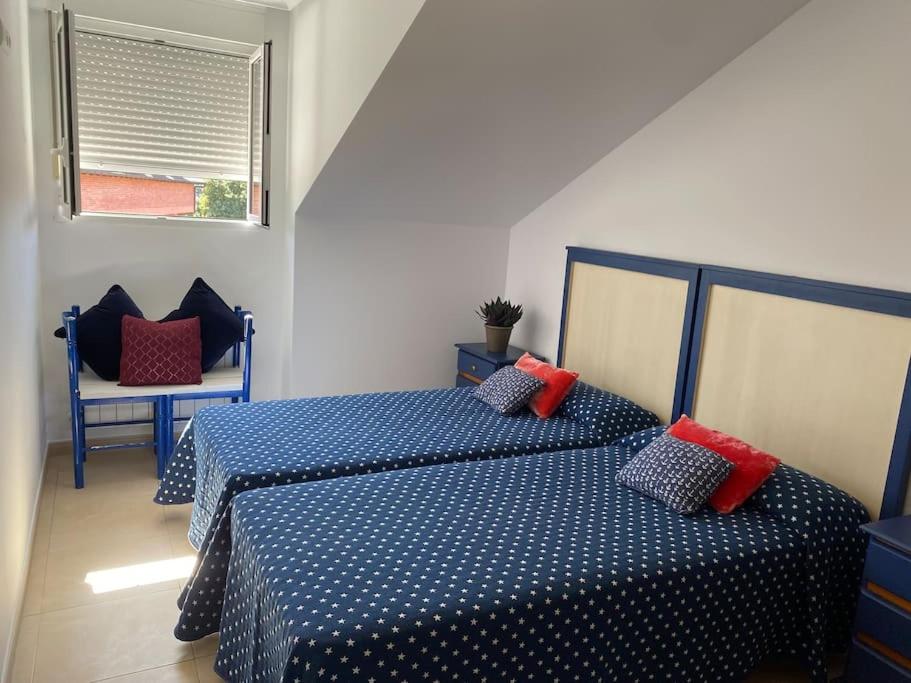 1 dormitorio con 2 camas y almohadas azules y rojas en ISLA, APARTAMENTO con PISCINA, en Isla