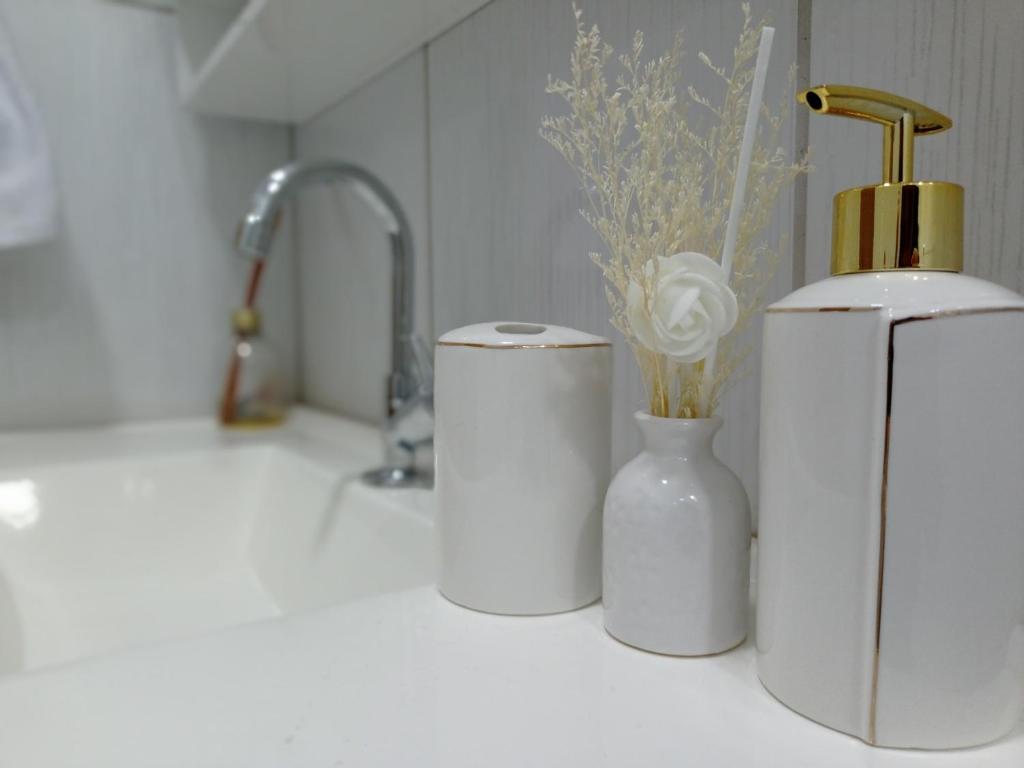 a kitchen counter with three white vases and a faucet at APTO COM VARANDA - 5KM DO AEROPORTO BSB - Nucleo Bandeirante in Brasilia