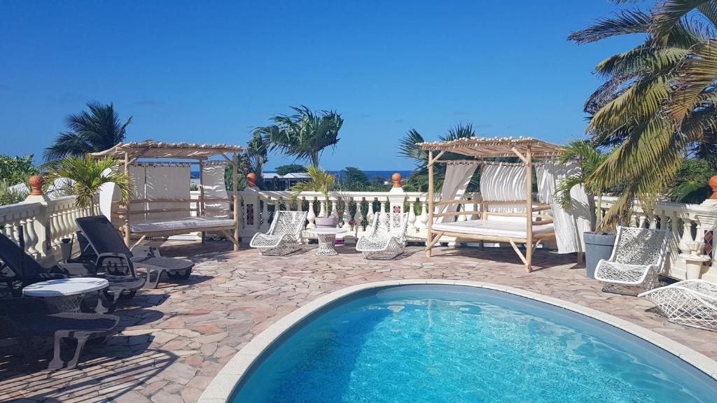 a swimming pool with chairs and a gazebo at LE MOULIN DE LA BAIE piscine vue mer in Le Moule