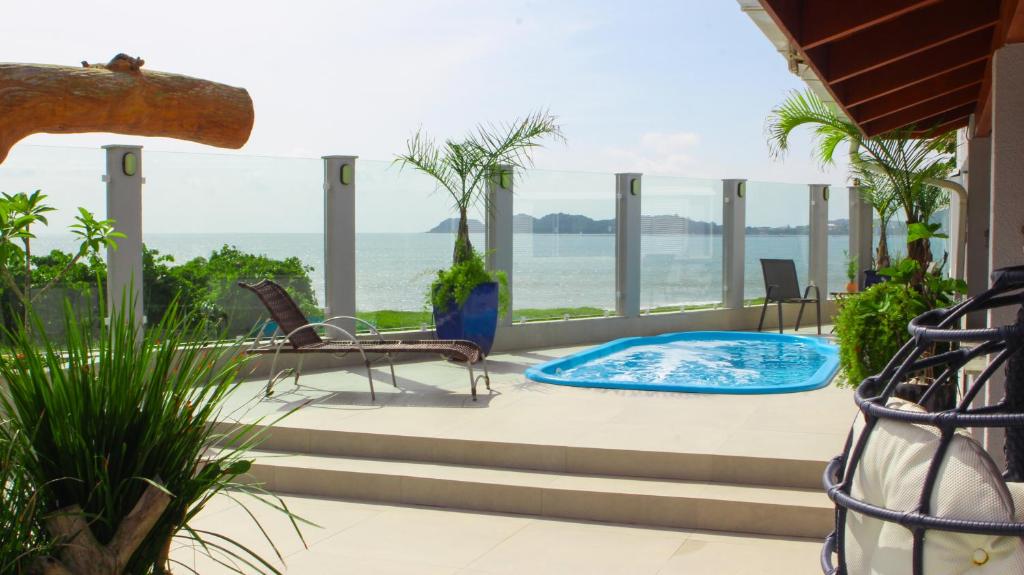une terrasse avec un bassin profond, des chaises et l'océan dans l'établissement Casa frente mar - Penha/SC, à Penha
