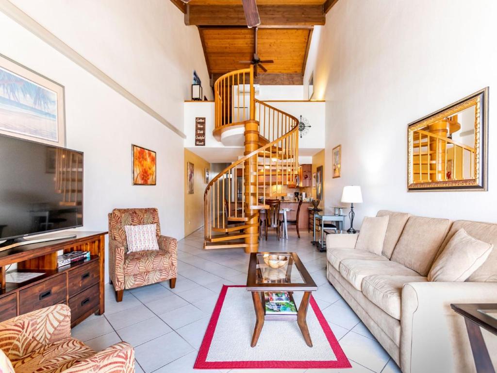 a living room with a couch and a spiral staircase at Kamaole Sands 8-402 - 2 Bedrooms, Pool Access, Spa, Sleeps 6 in Wailea