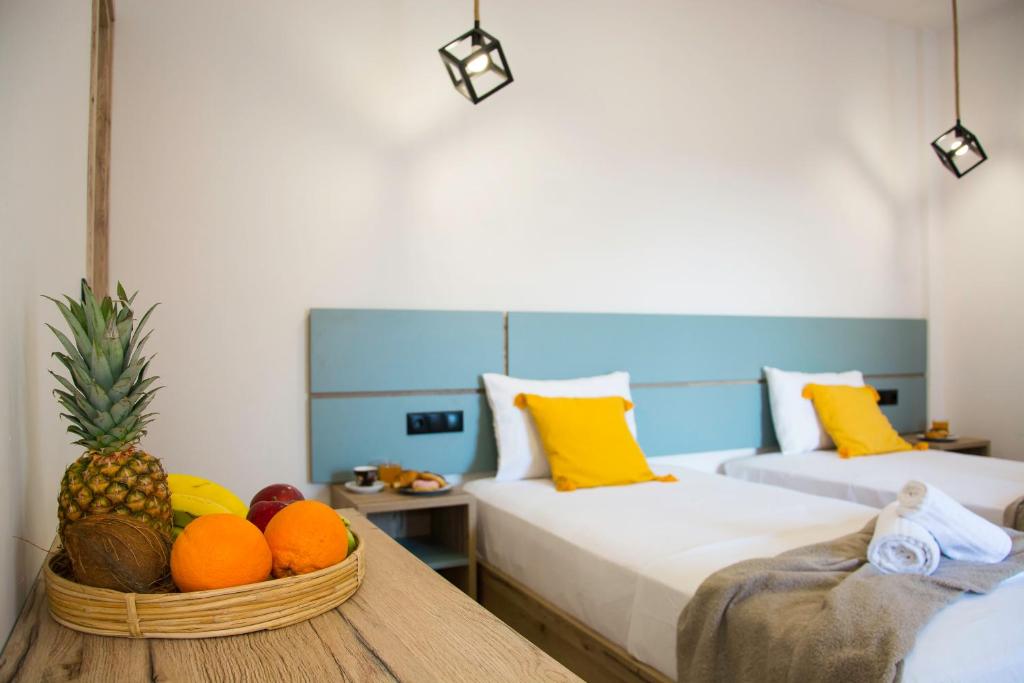 a room with two beds and a basket of fruit on a table at Big Max Guesthouse in Kavos