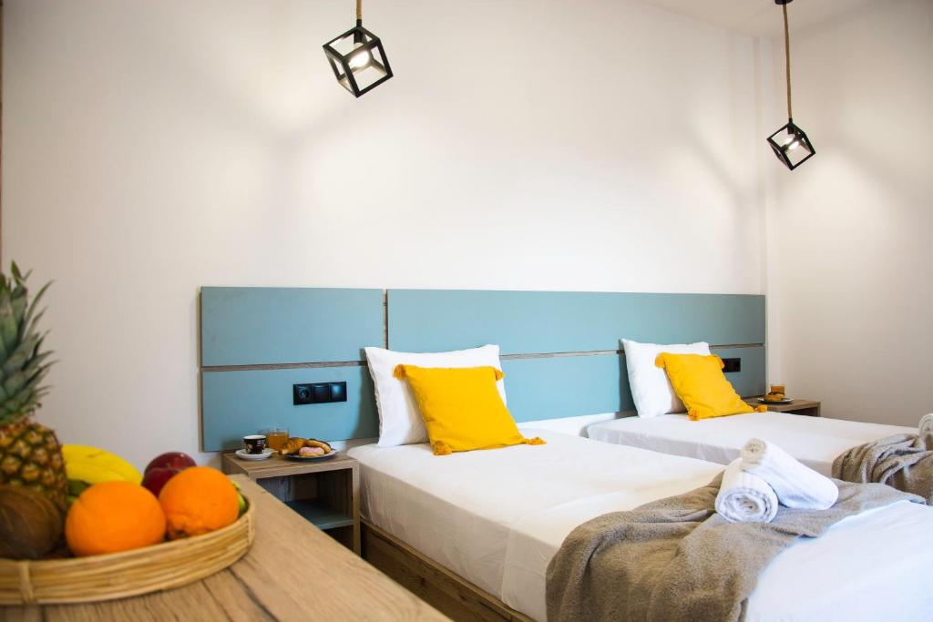 two beds with yellow pillows and oranges in a room at Big Max Guesthouse in Kavos