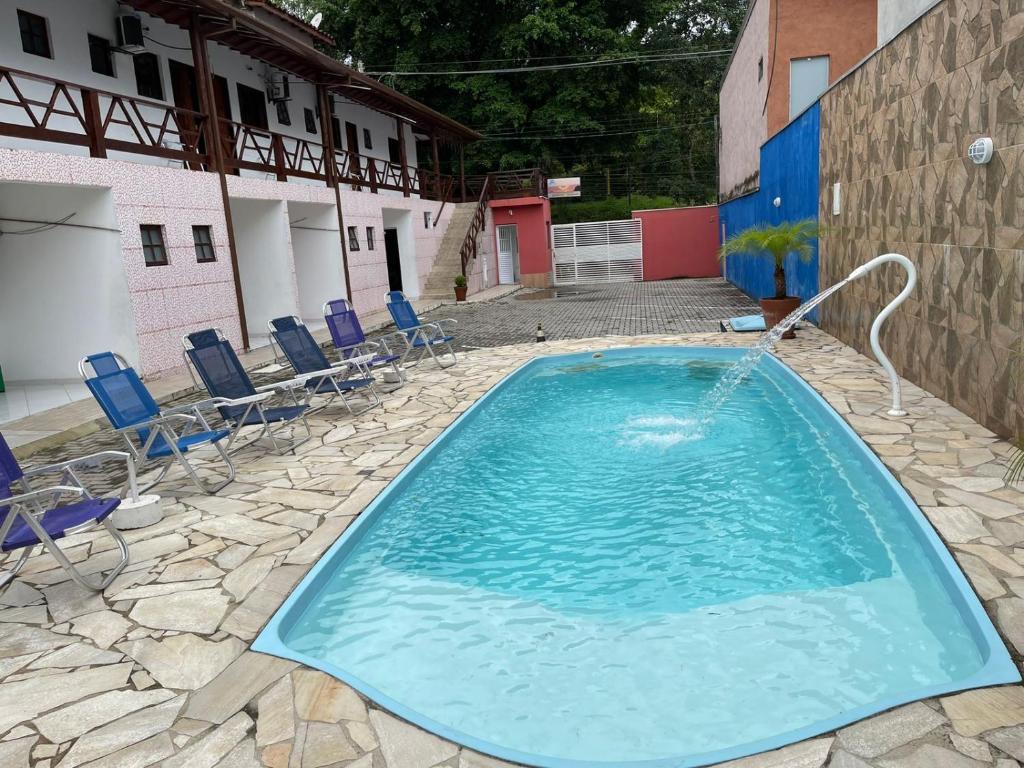 une grande piscine avec des chaises et un bâtiment dans l'établissement Pousada Canto Juquehy, à Juqueí